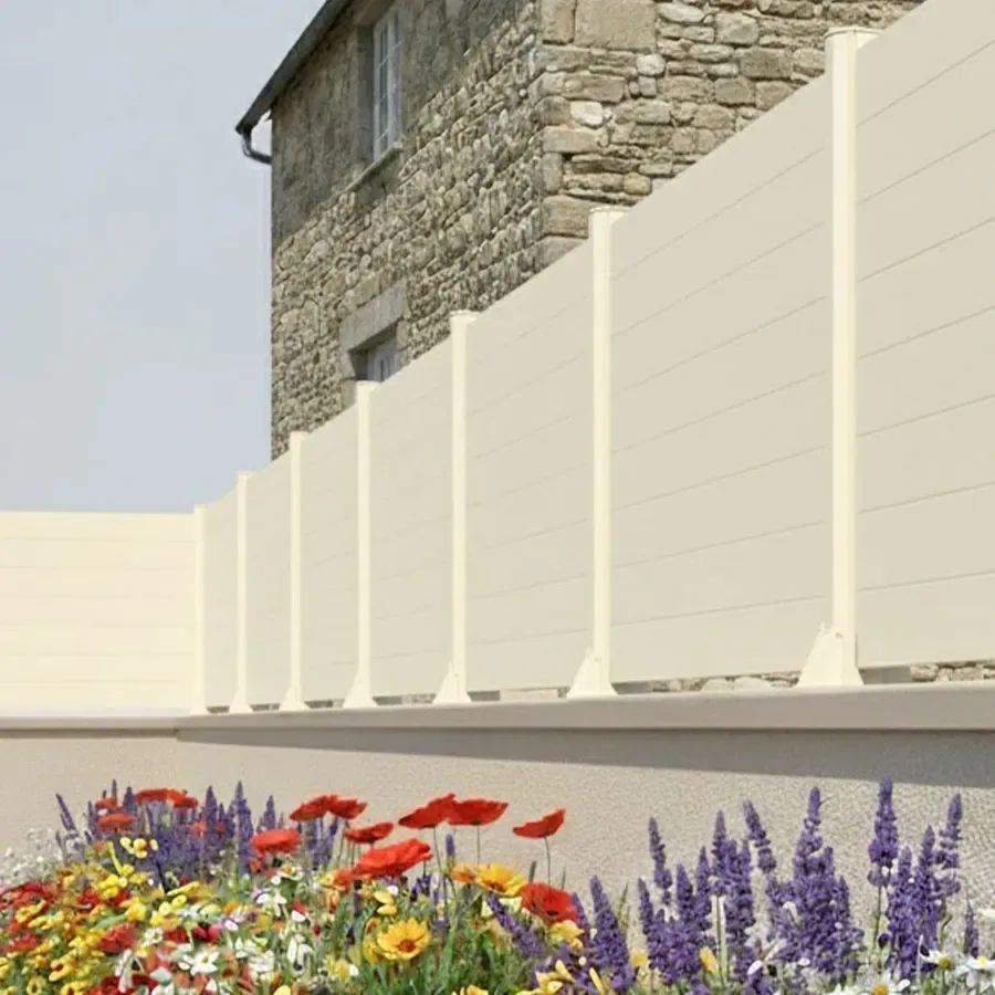 Clôture aluminium beige à petites lames pleines le long d'un mur en pierre, poteaux à platines visibles