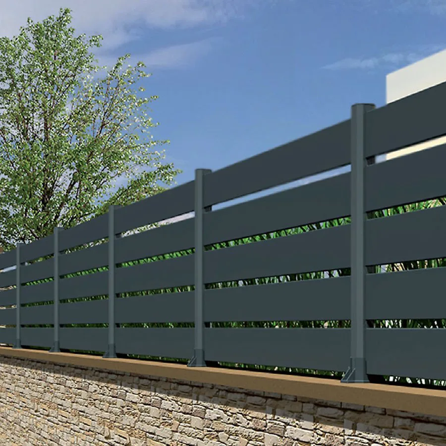 Longue clôture aluminium anthracite à lames ajourées sur un muret en pierre, végétation visible au travers