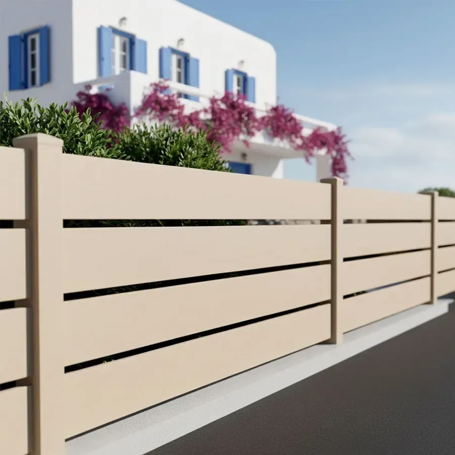 Clôture aluminium beige à grandes lames ajourées le long d'une rue, devant une maison aux volets bleus