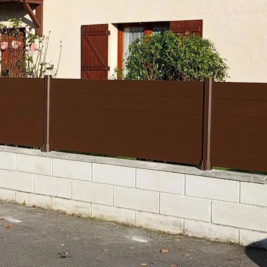 Clôture aluminium marron RAL 8019 à grandes lames pleines posée sur un muret en parpaings