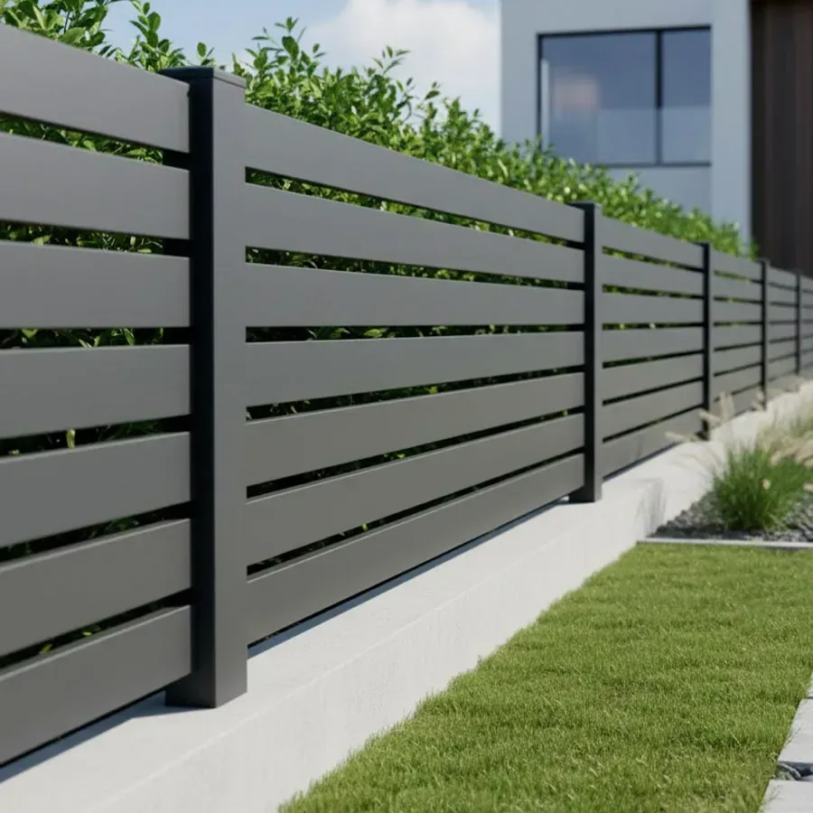 Clôture aluminium anthracite à petites lames ajourées bordant une pelouse, haie verte visible au travers