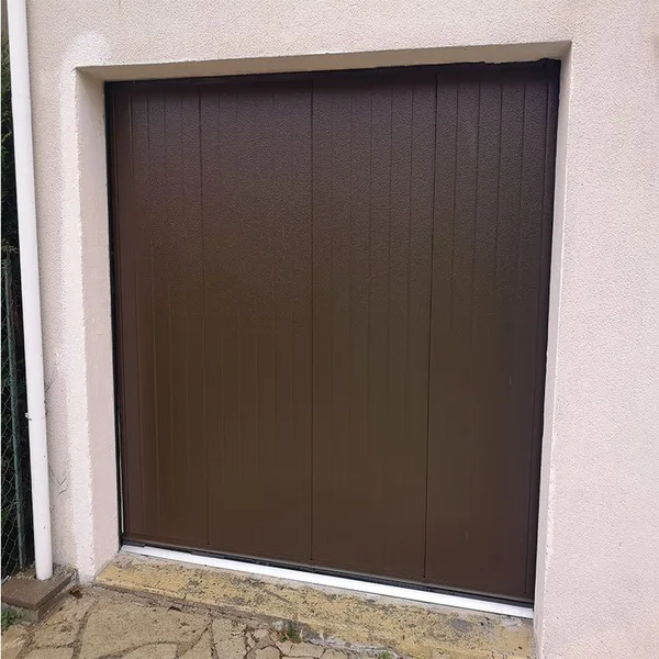 Porte de garage coulissante latérale de teinte brune sur une maison ancienne