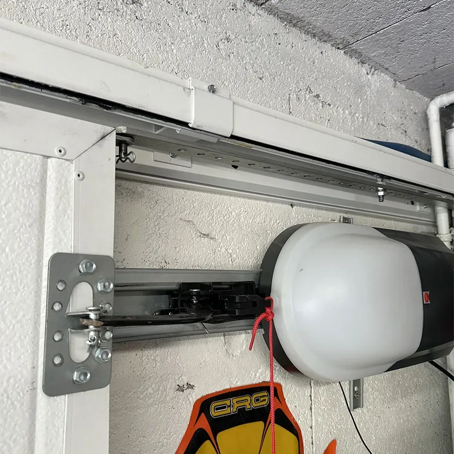 Moteur d'une porte de garage à enroulement latéral installé sur son rail le long de la paroi
