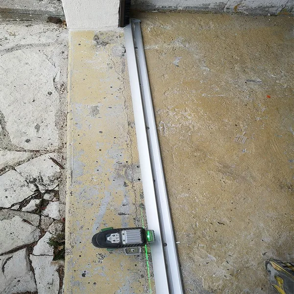 Rail inférieur en aluminium anodisé posé au sol le long du mur du garage