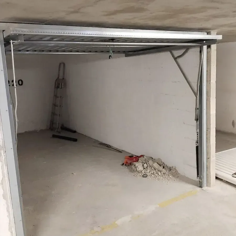 Porte de garage basculante ouverte, tablier rangé à l'horizontale sous le plafond d'un box