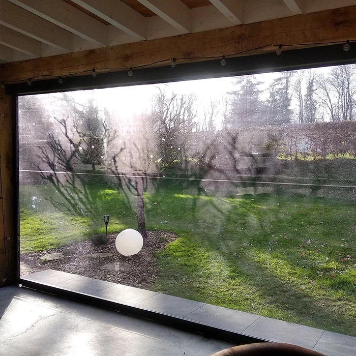 Vue depuis l'intérieur à travers un store à toile Cristal : le jardin est parfaitement net