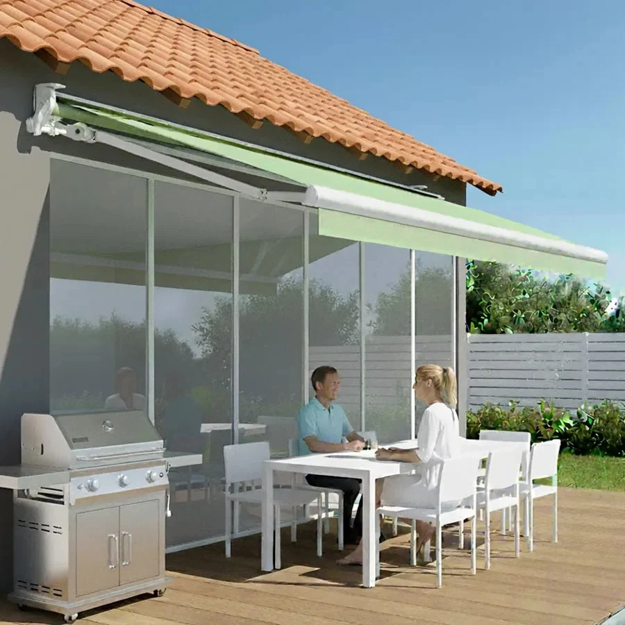 Store banne Maxi Design 2 bras vert pâle déployé au-dessus d'une terrasse de maison