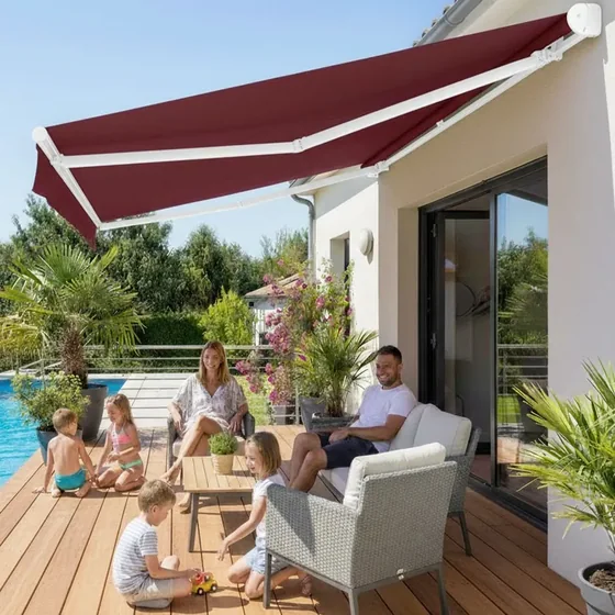 Store banne traditionnel bordeaux déployé au-dessus d'une terrasse de piscine