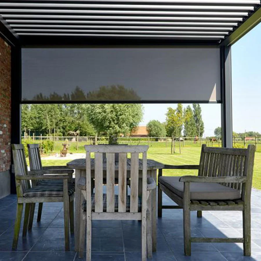 Store vertical à toile Soltis 92 grise déployé sous une pergola aluminium, la campagne reste visible à travers