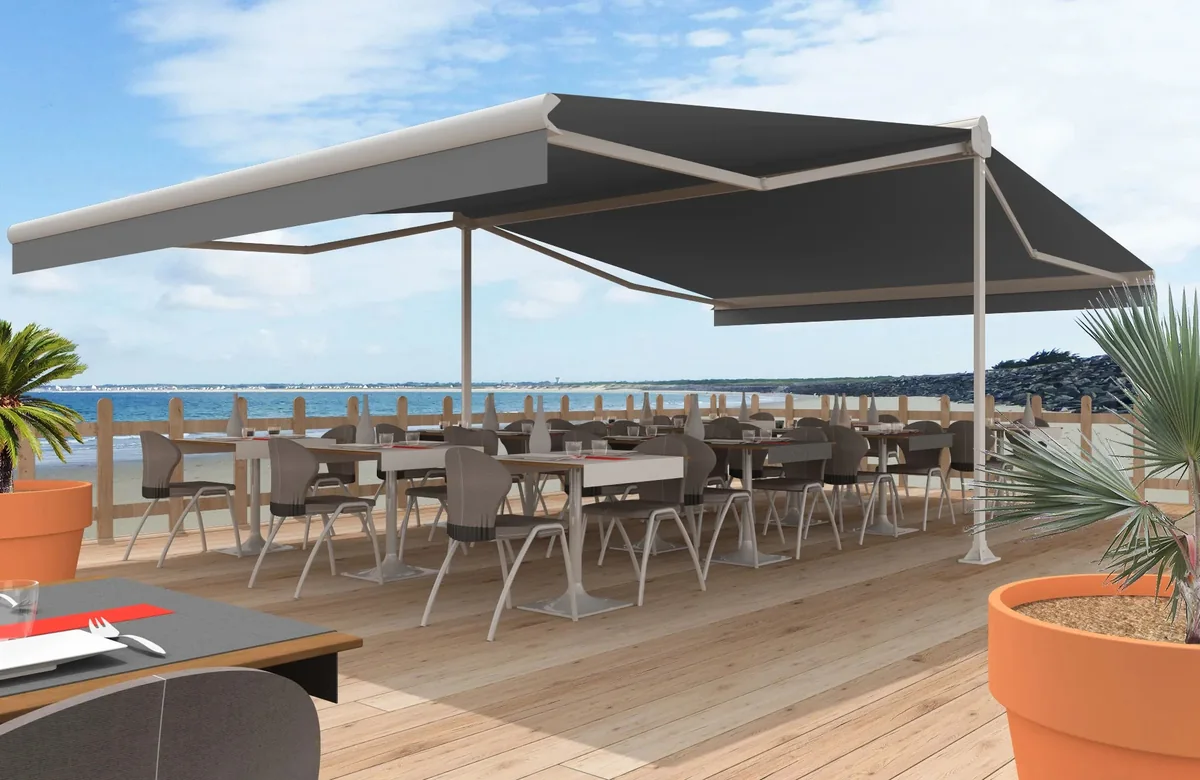Deux stores terrasse double pente XXL alignés au-dessus d'une terrasse de restaurant en bord de mer