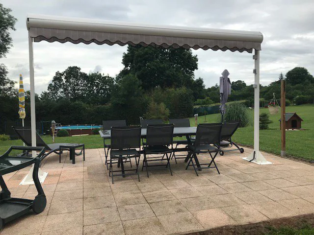 Store terrasse double pente crème vu de côté au-dessus d'un salon de jardin