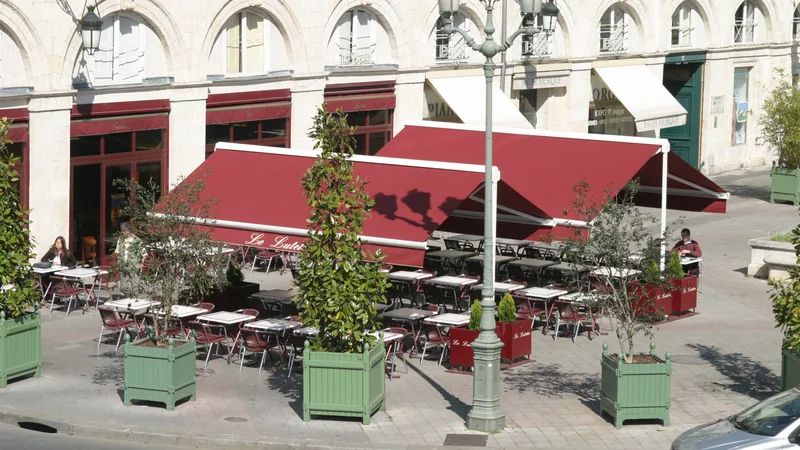 Deux stores terrasse double pente rouges sur la terrasse d'une brasserie