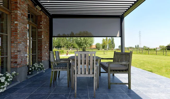Vue depuis la terrasse : store vertical déployé filtrant la lumière sur le jardin