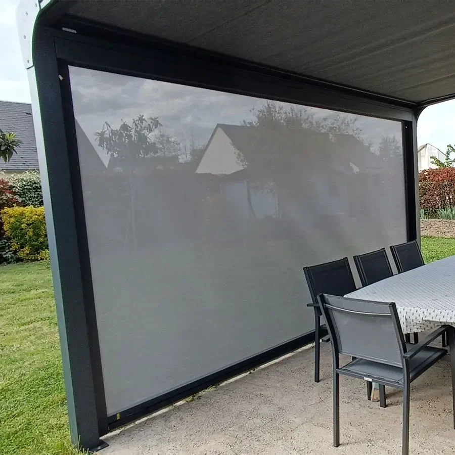 Store vertical Dickson Sunworker Open gris déployé sous une pergola aluminium, la vue reste visible à travers la toile