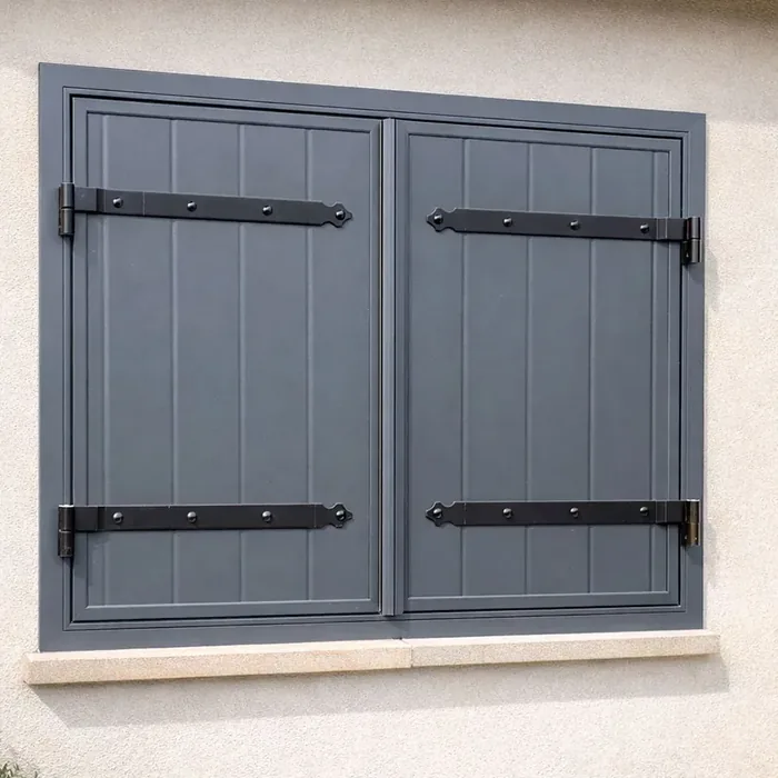 Volet battant aluminium gris anthracite avec pentures noires sur façade en enduit clair