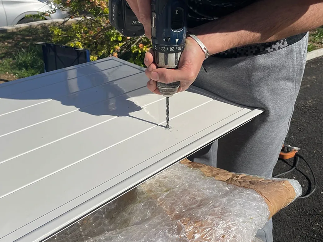 Penture noire à bout festonné vissée sur un volet battant aluminium blanc