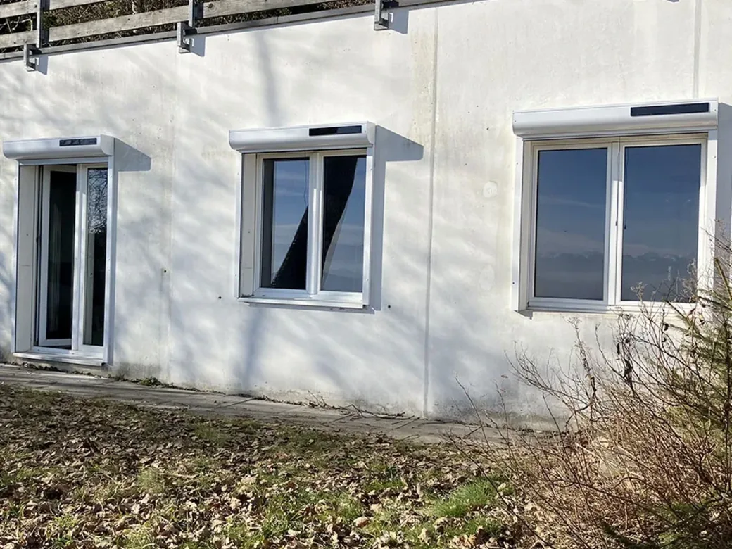 Volets roulants solaires posés en applique sur une façade, plusieurs fenêtres équipées