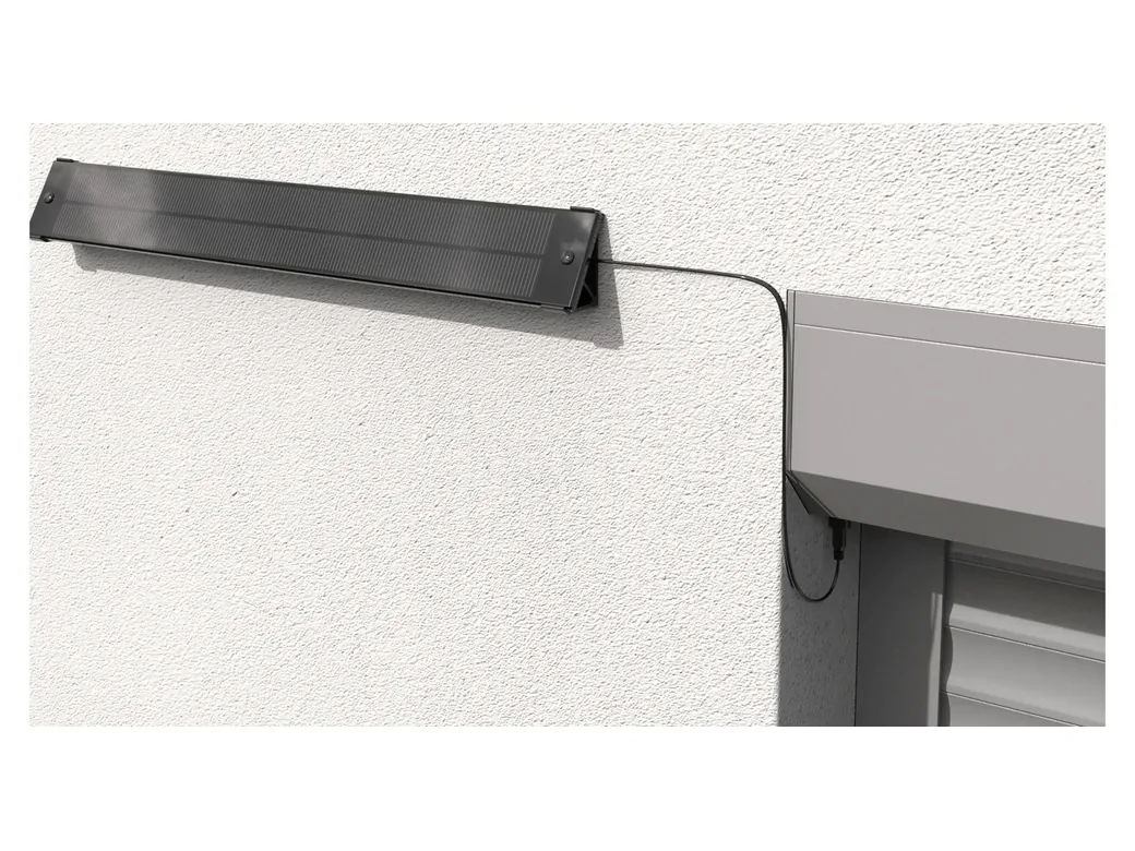 Panneau solaire déporté fixé sur le mur à côté du coffre, relié par un câble noir