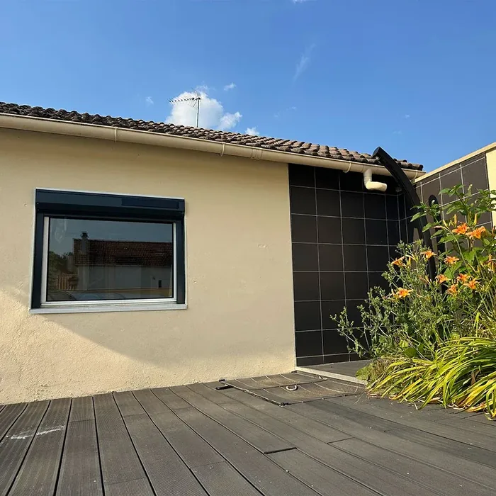 Volet roulant solaire anthracite sur une fenêtre donnant sur une terrasse en bois