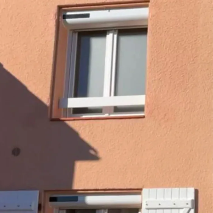 Volet roulant solaire blanc sur une façade en crépi ocre