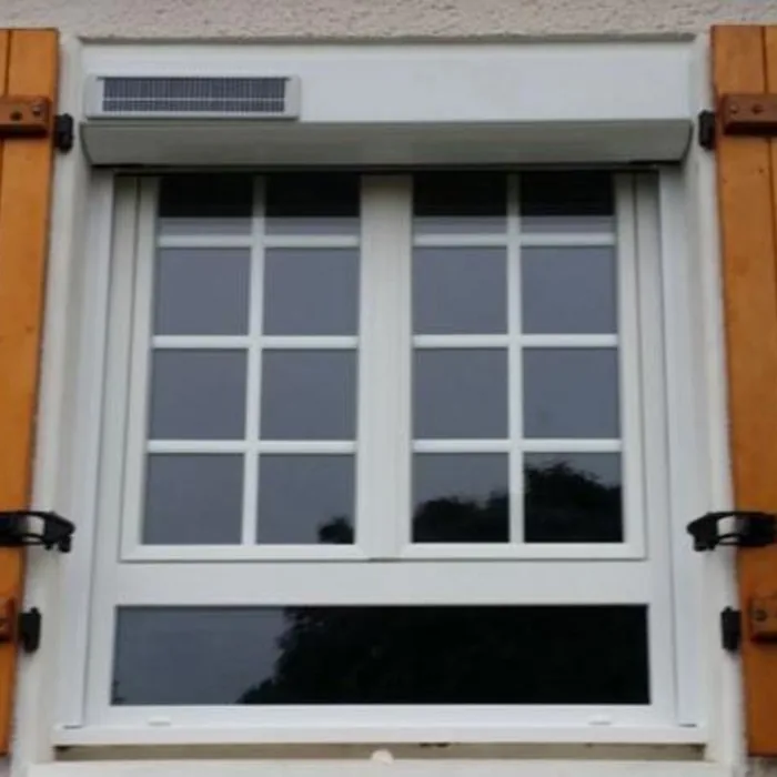 Volet roulant solaire blanc posé devant une fenêtre encadrée de volets battants en bois